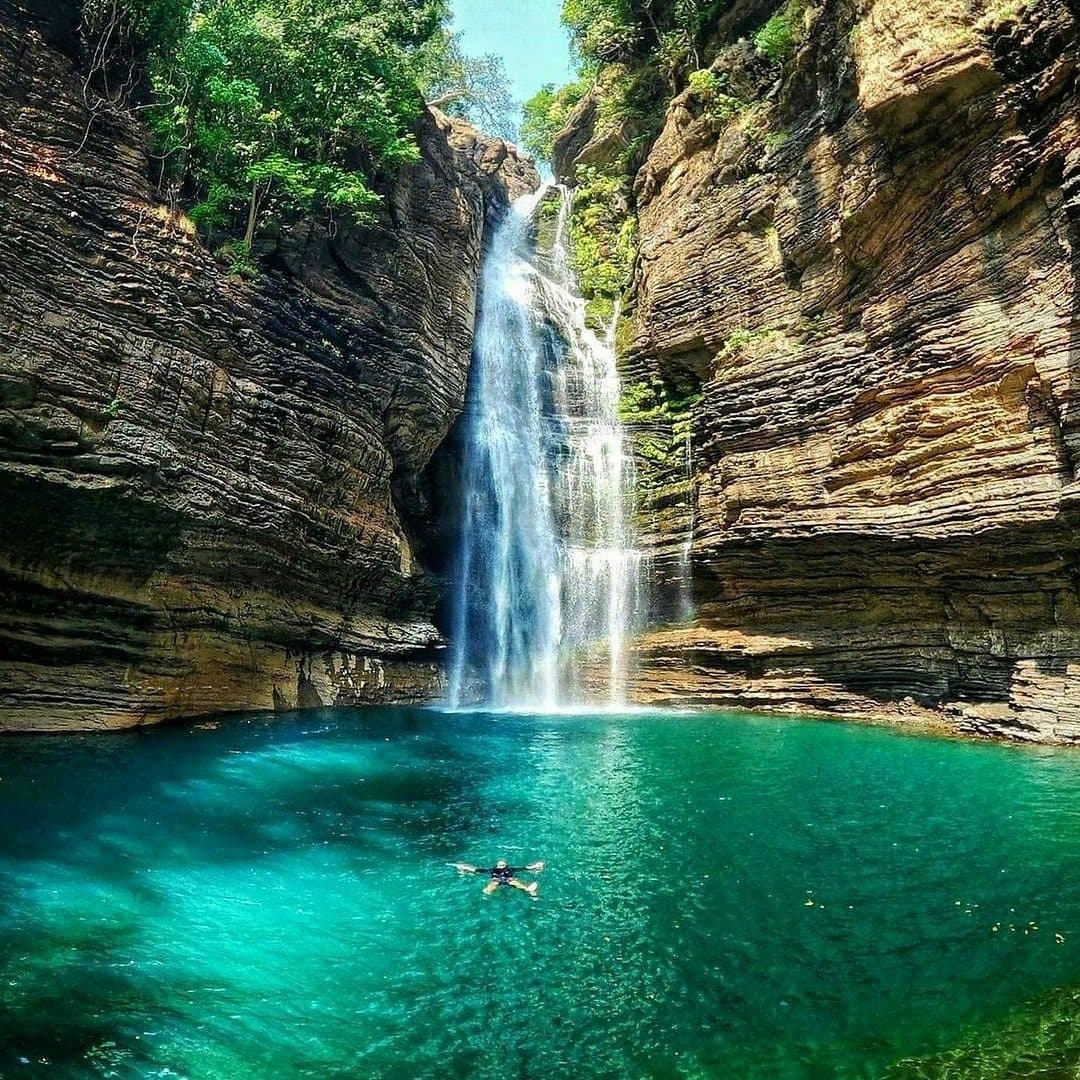 A waterfall falling into a turquoise forest pool