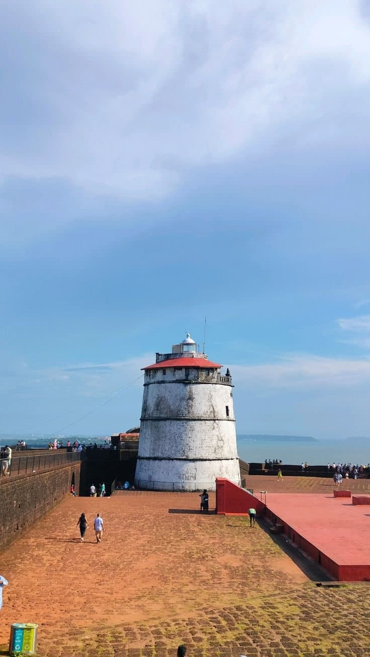 Fort Aguada's lighthouse against a wide coastal sky